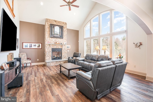 living area with dark wood-style floors, high vaulted ceiling, a fireplace, arched walkways, and ceiling fan