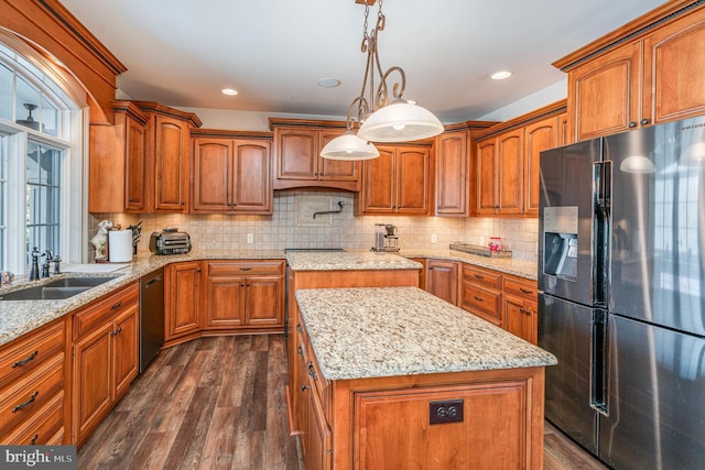 kitchen with refrigerator with ice dispenser, a sink, a center island, brown cabinetry, and dishwasher