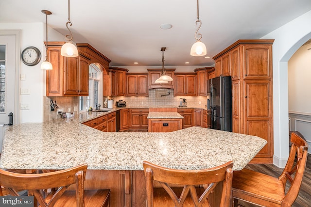 kitchen with a sink, a peninsula, brown cabinetry, and freestanding refrigerator