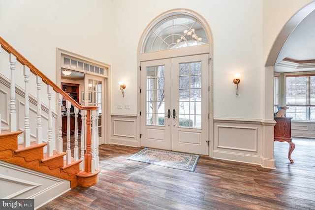 foyer entrance with wood finished floors, stairway, french doors, and arched walkways