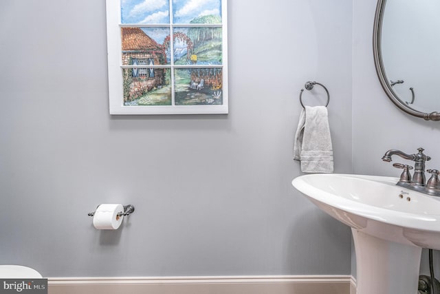 bathroom with toilet, a wealth of natural light, and a sink