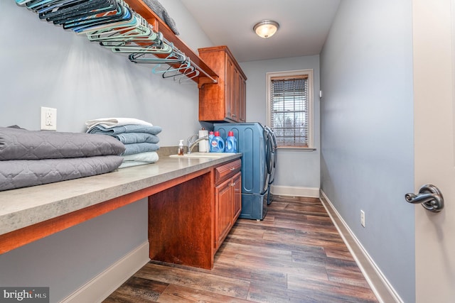 washroom with a sink, wood finished floors, cabinet space, separate washer and dryer, and baseboards