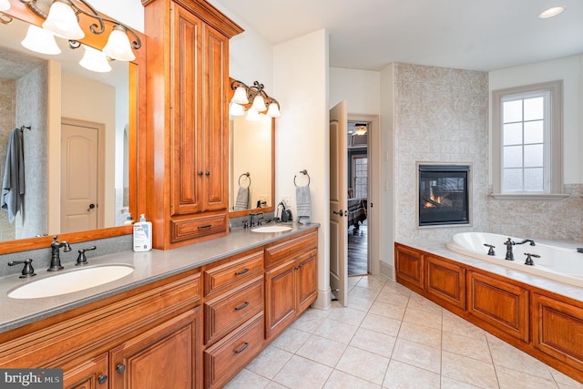 full bathroom with tile patterned floors, double vanity, a tile fireplace, and a sink