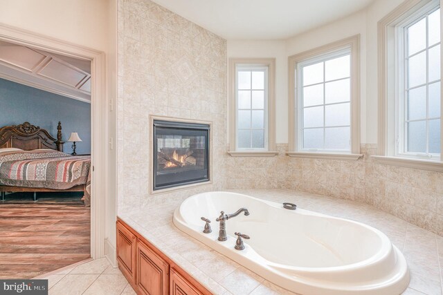 ensuite bathroom featuring tile patterned floors, a bath, ensuite bathroom, and a tile fireplace