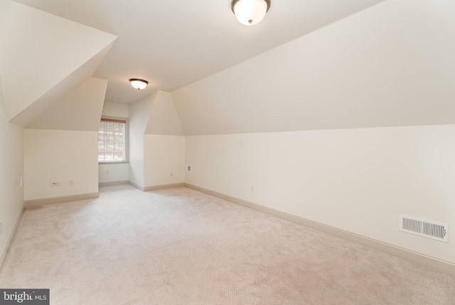 bonus room with vaulted ceiling, baseboards, visible vents, and light carpet