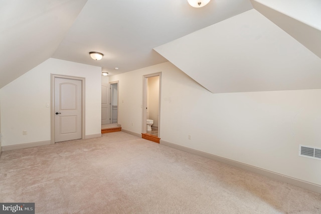 additional living space featuring lofted ceiling, baseboards, visible vents, and light carpet