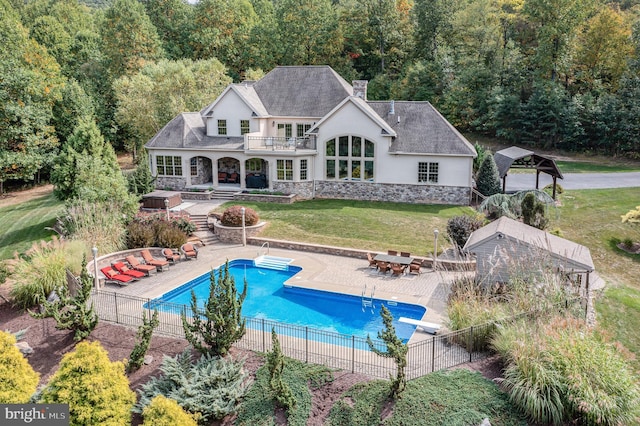 view of pool with a fenced in pool, fence, a lawn, a view of trees, and a patio