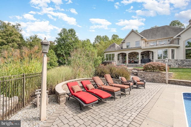 view of patio with a balcony and fence