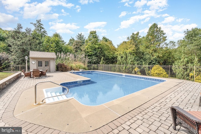 view of swimming pool featuring a fenced in pool, fence, a storage structure, an outdoor structure, and a patio