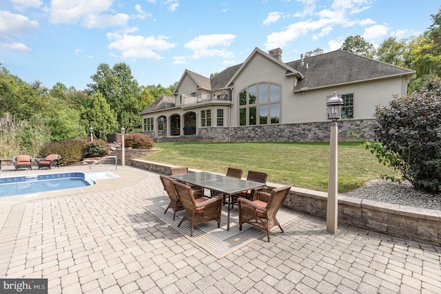 back of property with stucco siding, stone siding, a lawn, and a chimney