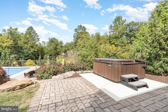 view of patio with a pool, fence, and a hot tub