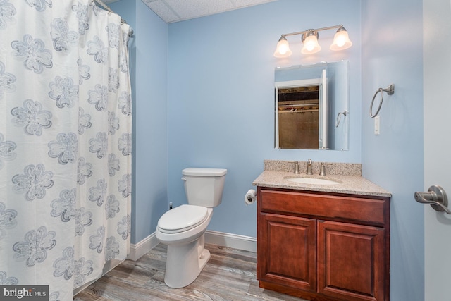 bathroom with toilet, curtained shower, wood finished floors, baseboards, and vanity