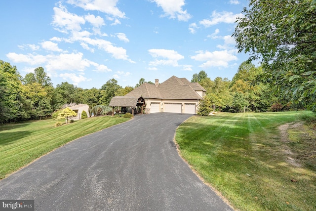 view of front of property featuring aphalt driveway, an attached garage, a front lawn, and a chimney