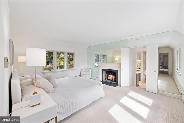 bedroom featuring light carpet, connected bathroom, and vaulted ceiling