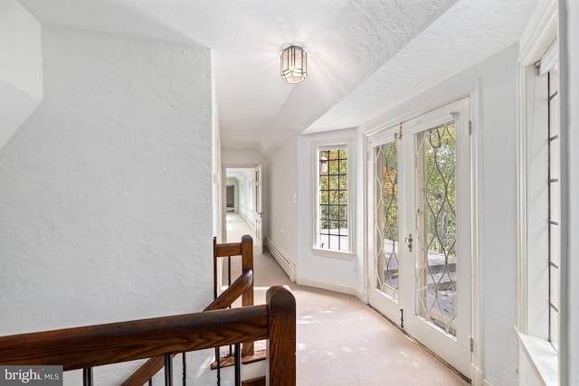 doorway with light carpet, french doors, a baseboard heating unit, and a textured ceiling