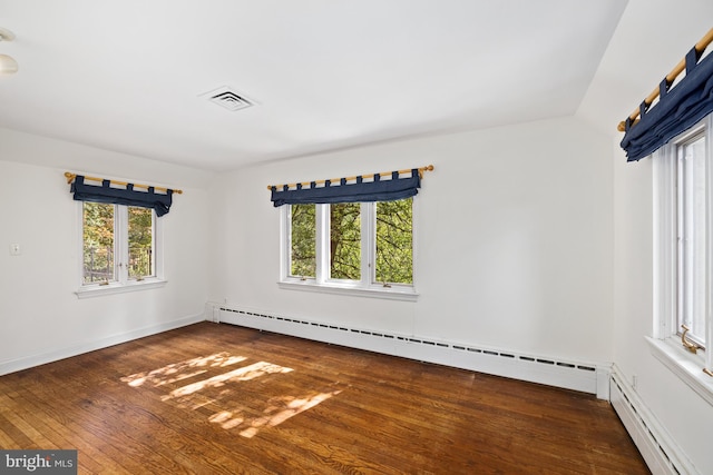 empty room featuring dark wood-type flooring, a baseboard radiator, and plenty of natural light