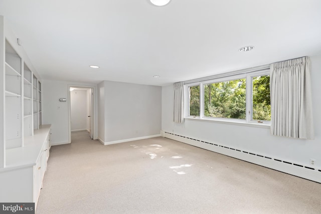 carpeted empty room with a baseboard heating unit