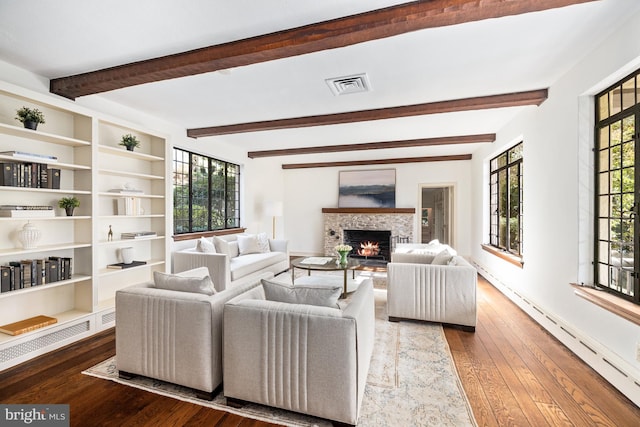 living room with beam ceiling, hardwood / wood-style flooring, and a stone fireplace