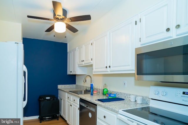 kitchen with light stone counters, appliances with stainless steel finishes, white cabinetry, light wood-type flooring, and sink