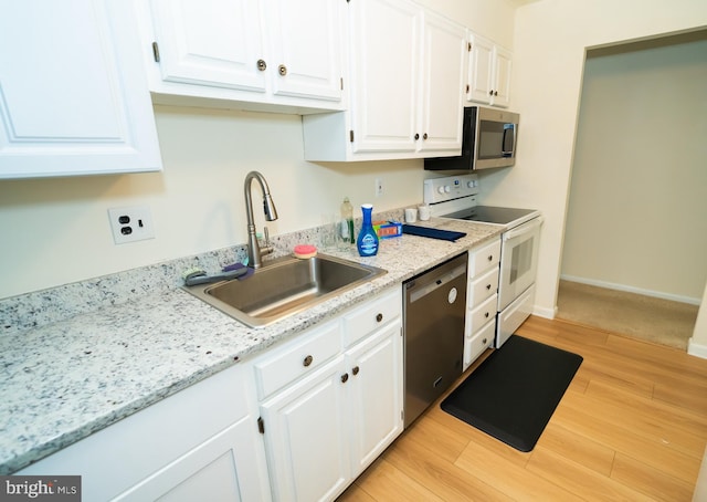 kitchen featuring light stone counters, appliances with stainless steel finishes, white cabinetry, light hardwood / wood-style floors, and sink