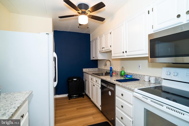 kitchen with sink, stainless steel appliances, white cabinets, light stone counters, and light hardwood / wood-style flooring