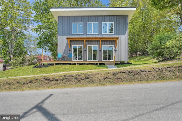 back of property with a deck and a lawn