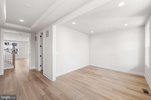 spare room featuring light hardwood / wood-style flooring and a tray ceiling