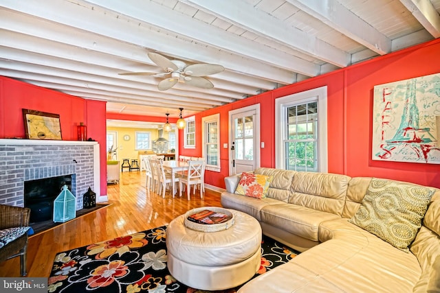 living room featuring wood-type flooring, a brick fireplace, ceiling fan, wooden ceiling, and beam ceiling