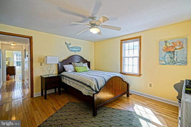 bedroom with multiple windows, wood-type flooring, and ceiling fan