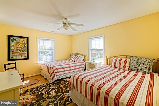 bedroom with hardwood / wood-style flooring, multiple windows, and ceiling fan