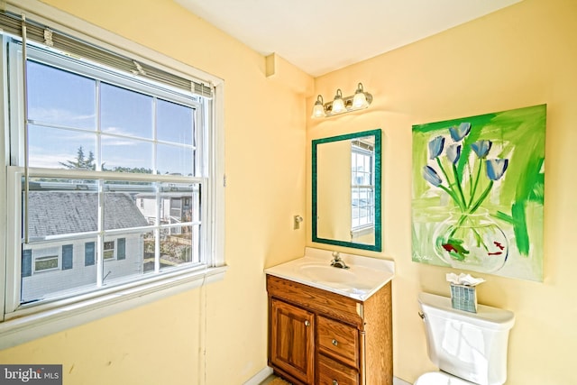 bathroom featuring vanity, toilet, and a healthy amount of sunlight