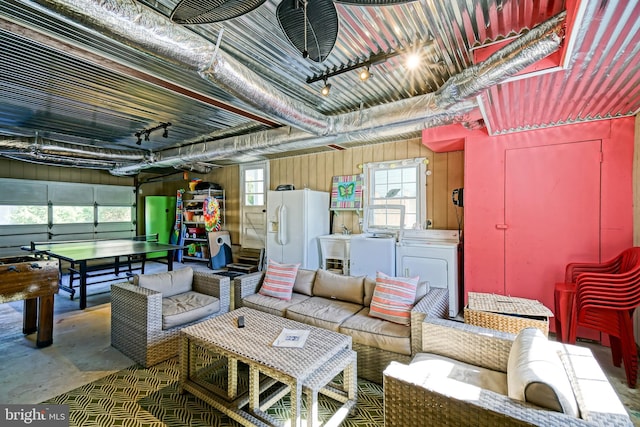 garage featuring white fridge with ice dispenser, washer / clothes dryer, and wooden walls