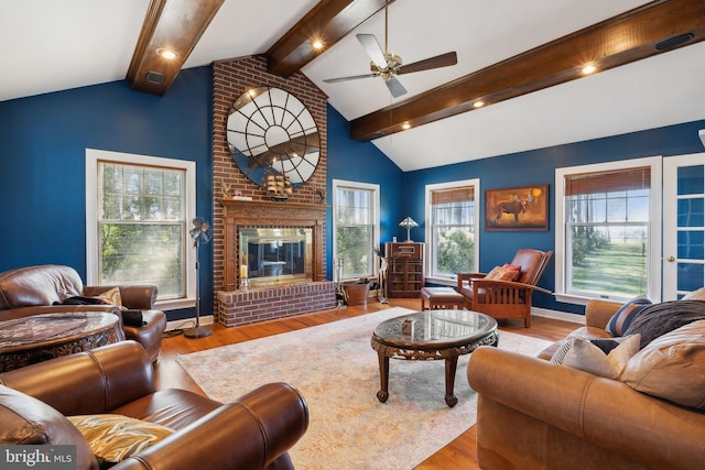 living room with lofted ceiling with beams, ceiling fan, light wood-type flooring, and a brick fireplace