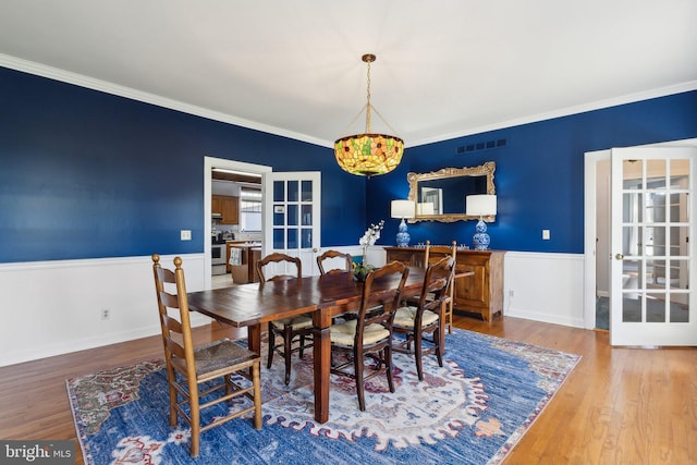 dining room with ornamental molding, hardwood / wood-style floors, and french doors