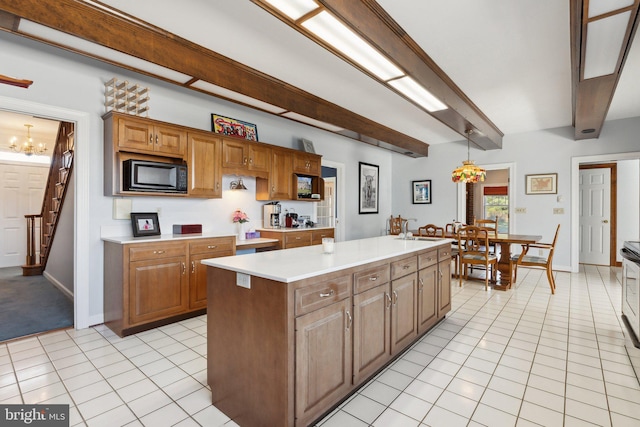 kitchen featuring light tile patterned flooring, a center island, black microwave, and decorative light fixtures