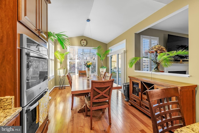 dining room featuring lofted ceiling and light hardwood / wood-style flooring