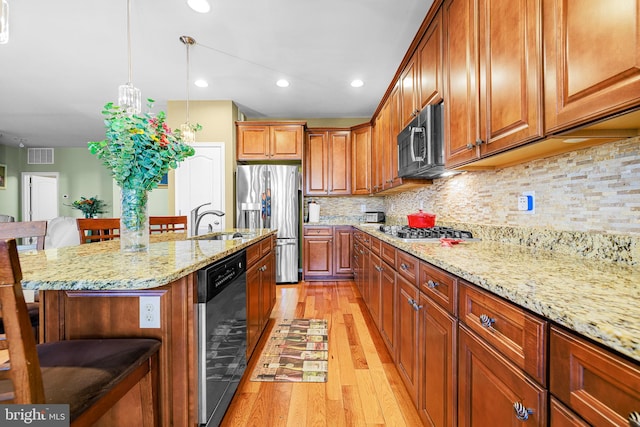 kitchen with a center island with sink, stainless steel appliances, wine cooler, light wood-type flooring, and a kitchen bar