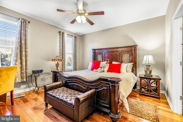 bedroom featuring ceiling fan, multiple windows, and light hardwood / wood-style floors