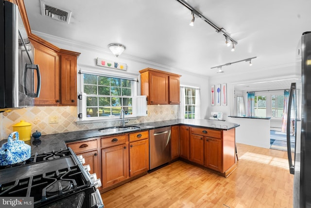 kitchen featuring kitchen peninsula, stainless steel appliances, crown molding, light wood-type flooring, and tasteful backsplash