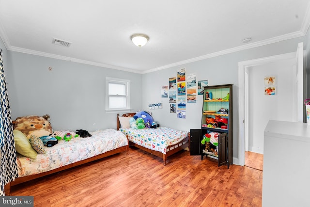 bedroom with ornamental molding and hardwood / wood-style floors