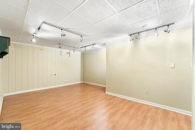 basement featuring rail lighting, wood-type flooring, and a drop ceiling