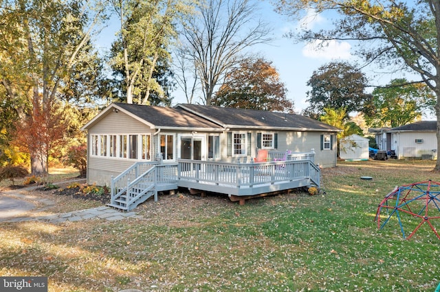 back of property with a deck, a lawn, and a sunroom