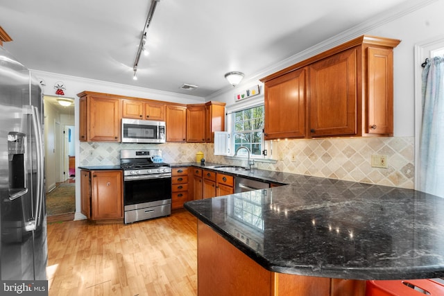 kitchen featuring appliances with stainless steel finishes, kitchen peninsula, light wood-type flooring, and crown molding