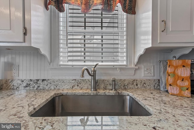 kitchen featuring light stone countertops, sink, and white cabinets