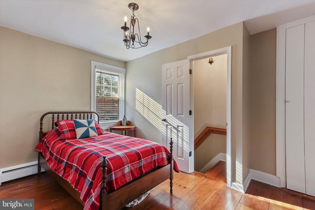 bedroom featuring a baseboard heating unit, a chandelier, and hardwood / wood-style floors