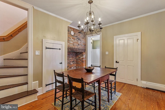 dining space featuring ornamental molding, light hardwood / wood-style flooring, an inviting chandelier, and a baseboard heating unit