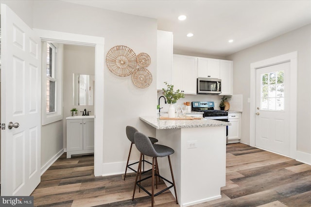 kitchen featuring a breakfast bar area, dark wood-type flooring, white cabinets, and stainless steel appliances