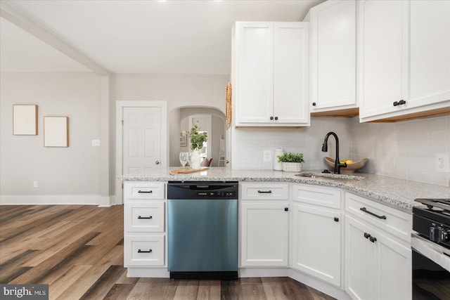 kitchen featuring stainless steel appliances, white cabinets, light stone counters, hardwood / wood-style flooring, and decorative backsplash