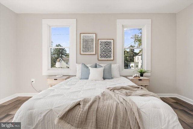 bedroom with multiple windows and dark hardwood / wood-style flooring