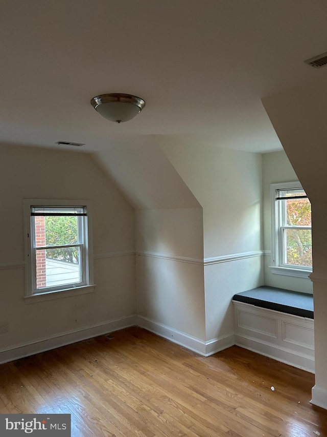 bonus room featuring vaulted ceiling, light wood-style flooring, visible vents, and a healthy amount of sunlight
